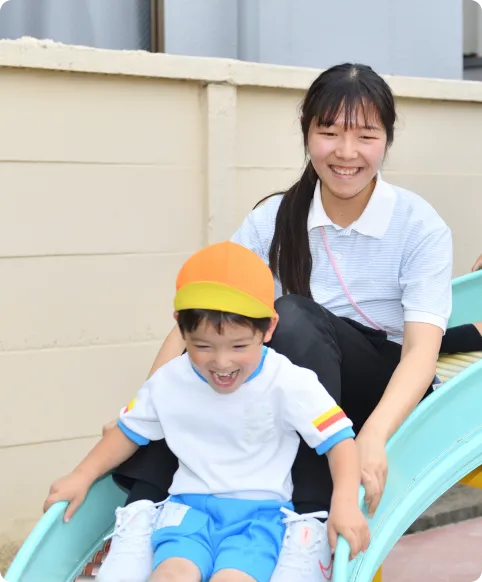 すべり台で子どもに寄り添う先生