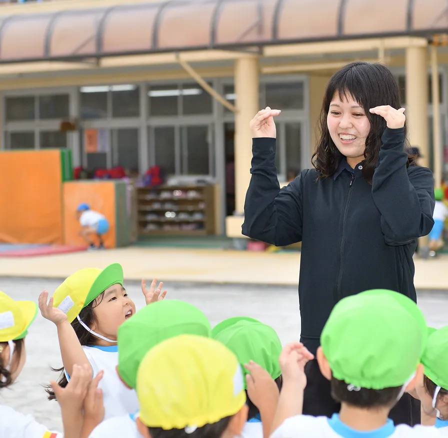 園庭で先輩の先生のサポートを受けながら体操をする先生